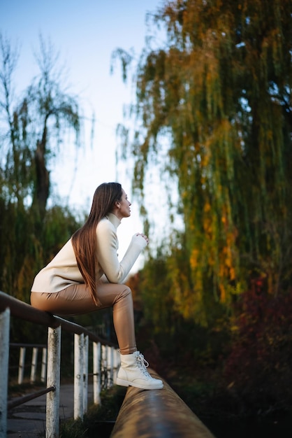 Foto giovane donna seduta sul ponte e che beve caffè