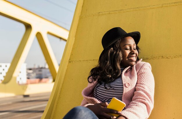 Photo young woman sitting on  bridge using smartphone