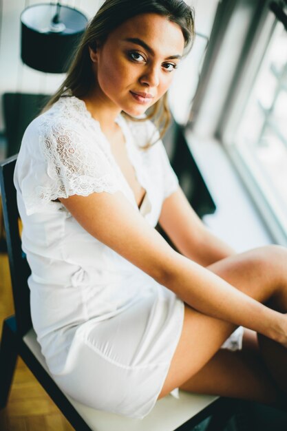 Photo young woman sitting by the window in the bedroom