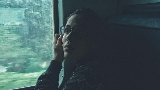 写真 電車の窓のそばに座っている若い女性