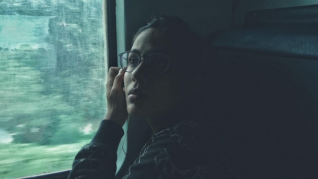 Photo young woman sitting by window in train