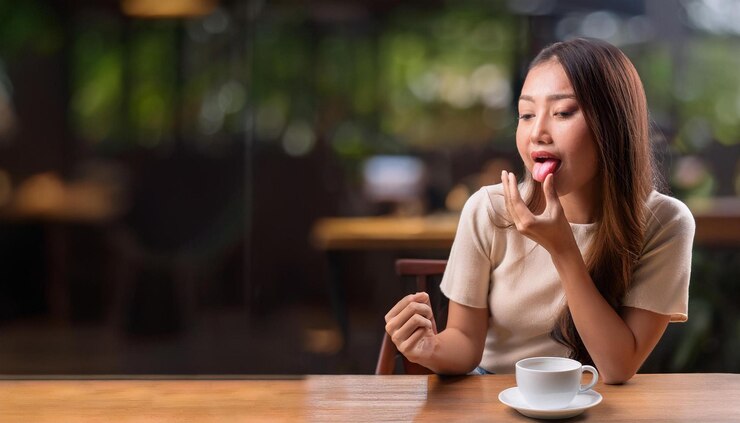 Photo カフェに座っている若い女性が舌を燃やした後痛みの表情で舌を握っています