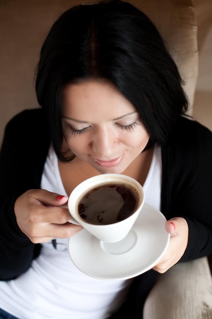 Foto giovane donna che si siede in un caffè che beve caffè