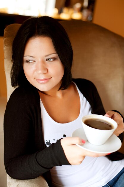 コーヒーを飲みながらカフェに座っている若い女性