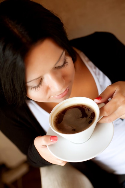 Foto giovane donna che si siede in un caffè che beve caffè