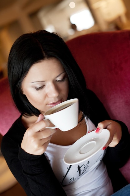 コーヒーを飲みながらカフェに座っている若い女性