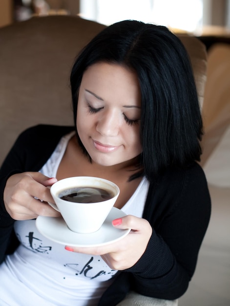 コーヒーを飲みながらカフェに座っている若い女性