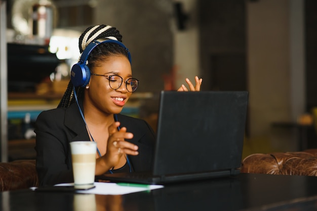 Молодая женщина, сидящая в кафе, работающая на ноутбуке