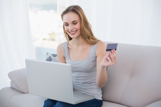 온라인 쇼핑을 위해 노트북을 사용하는 소파에 앉아 젊은 여자