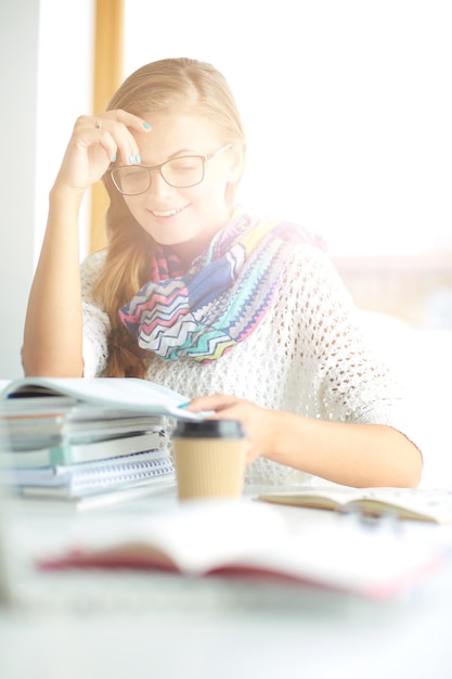 Young woman sitting at a desk among books Student