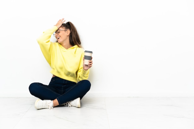 Young woman sitting on the floor holding a take away coffee has realized something and intending the solution