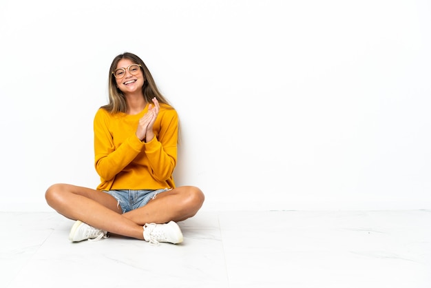 Photo young woman sitting on the floor isolated