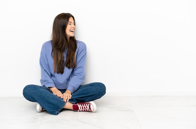 横向きで笑って床に座っている若い女性