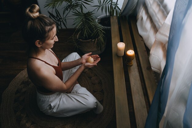 Photo young woman sitting on the floor lights candles enjoy meditation do yoga exercise at home mental