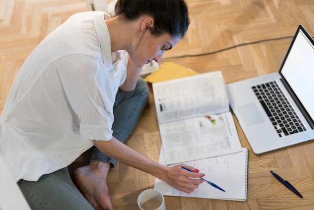 Young woman sitting on the floor looking at notepad