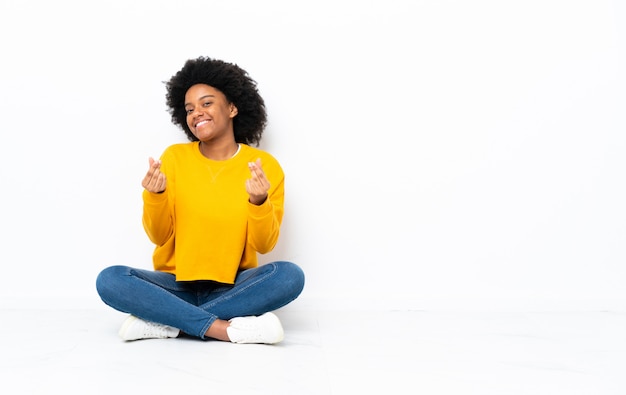 Young woman sitting on the floor making money gesture