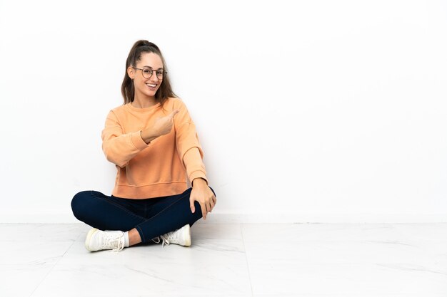 Young woman sitting on the floor pointing back