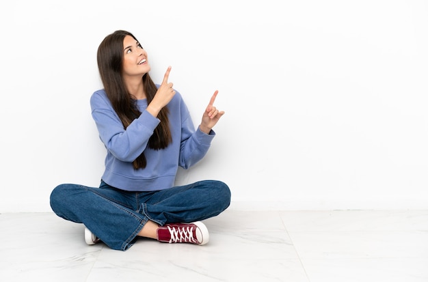 Young woman sitting on the floor pointing with the index finger a great idea