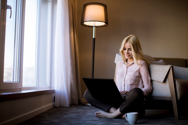 Young woman sitting on the floor in the room with laptop