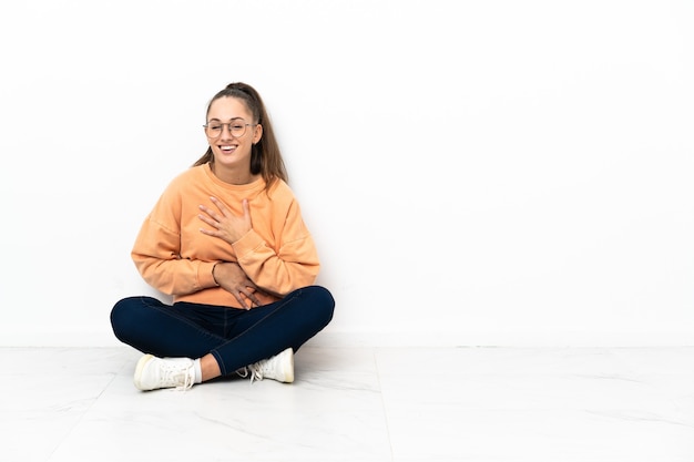 Foto giovane donna seduta sul pavimento sorridendo molto