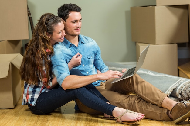 Young woman sitting on floor and using laptop in their new house