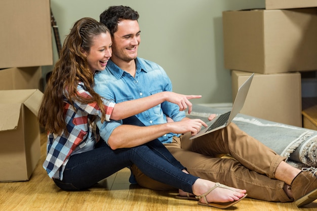 Young woman sitting on floor and using laptop in their new house