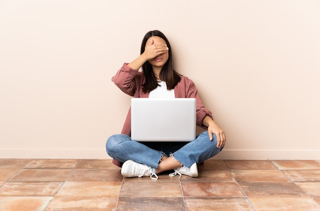 Young woman sitting on the floor with her laptop