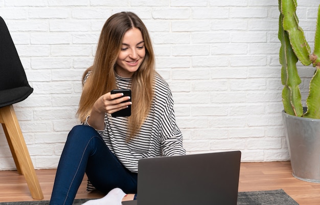 Young woman sitting on the floor with her laptop