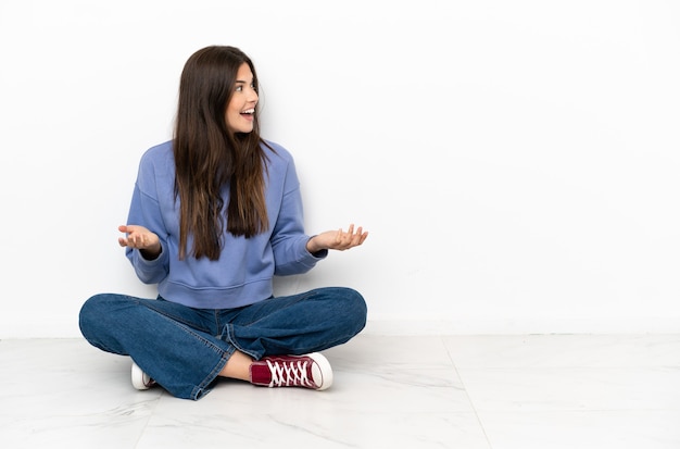 驚きの表情で床に座っている若い女性