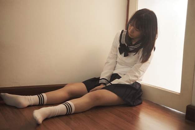 Young woman sitting on hardwood floor at home