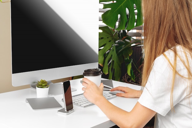 Young woman sitting at her desk in an office drinking coffee