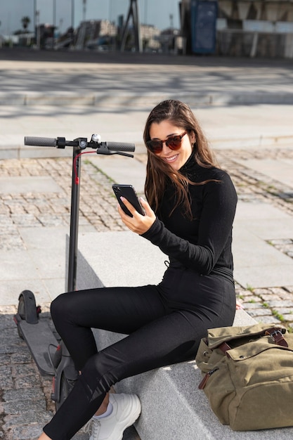 Photo young woman sitting next to her scooter