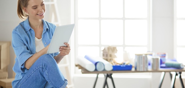 Young woman sitting at home and buying new furniture over the internet using a tablet computer