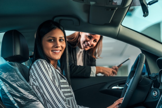 ブランドの新しい車に座っている若い女性。