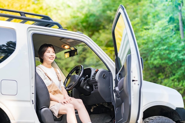 写真 笑顔で車の運転席に座っている若い女性