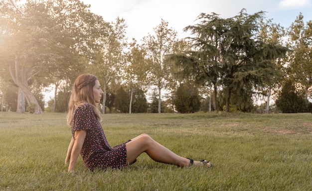 無限大を見ている公園の芝生に座っている若い女性。セレクティブフォーカス。