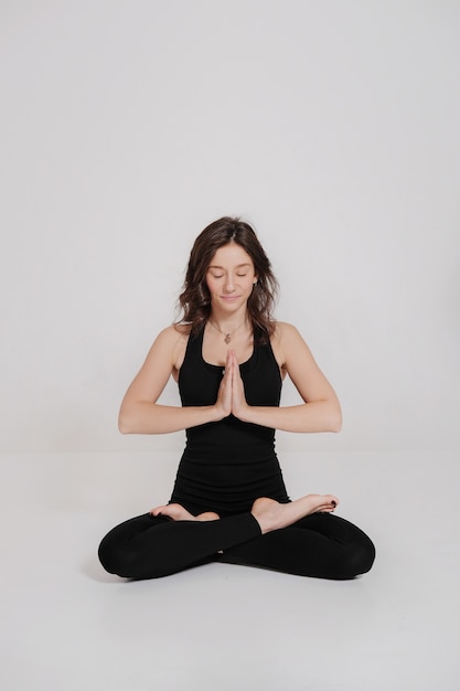 Young woman sitting in lotus posture in yoga class