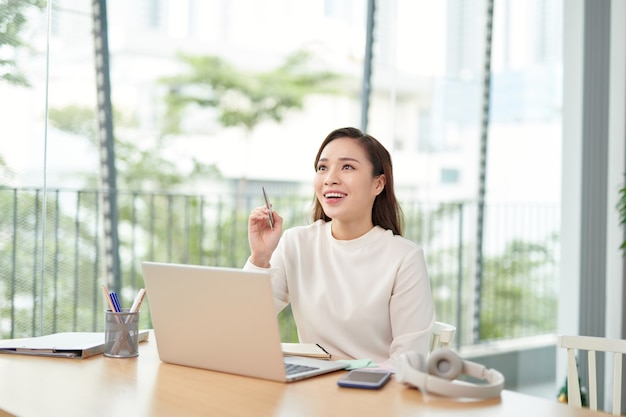 ノートパソコンでオフィスのテーブルに座っている若い女性