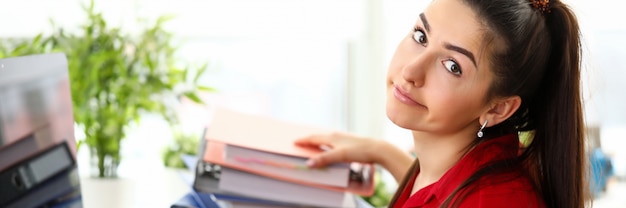 Young woman sitting in office with heap of documents and feeling stressed