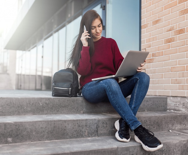 Фото Молодая женщина сидит на лестнице с ноутбуком
