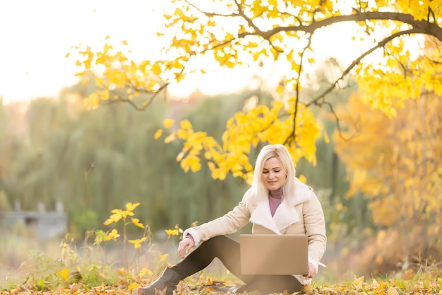 Young woman sitting in park with laptop