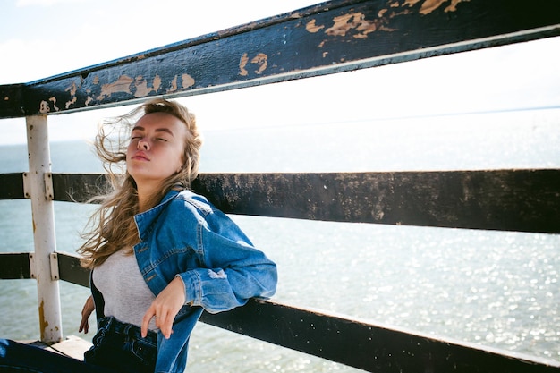 Photo young woman sitting on pier over sea against sky