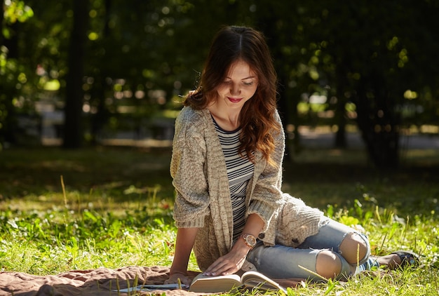 Young woman sitting in the quiet green grass and reading a book