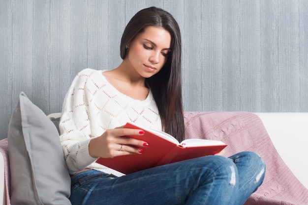 Young woman sitting read book couch sofa at home