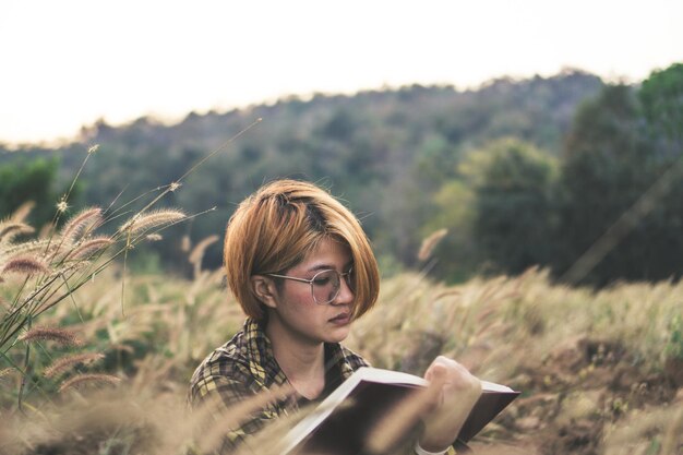 Foto giovane donna seduta a leggere un libro in natura la sera