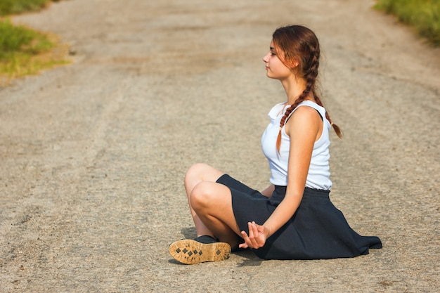 Young woman sitting on the road and meditating, relax.