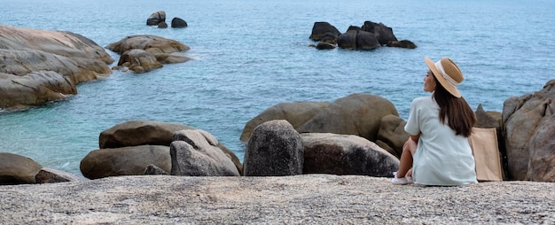 A young woman sitting on the rock by the sea