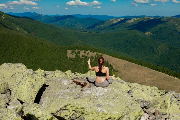 Молодая женщина, сидя на скале и глядя на горизонте.