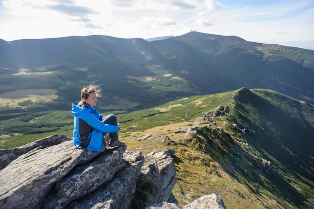 Young woman sitting on a rock in the mountains