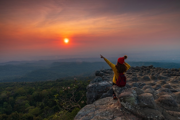 Photo young woman sitting on a rock in the mountains